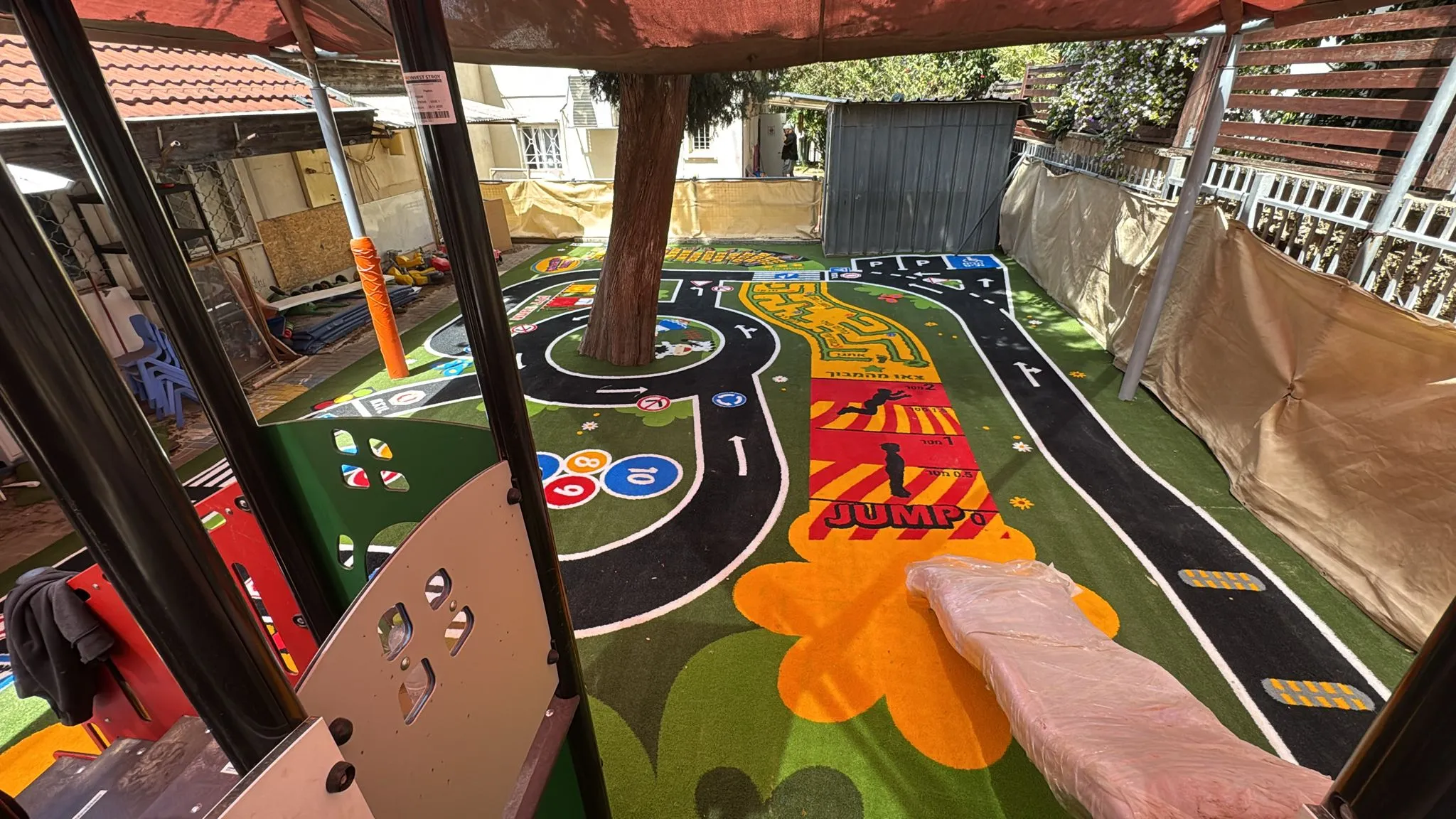 Elevated view of the winding road circuit and orange roundabout fitted around the kindergarten’s central tree
