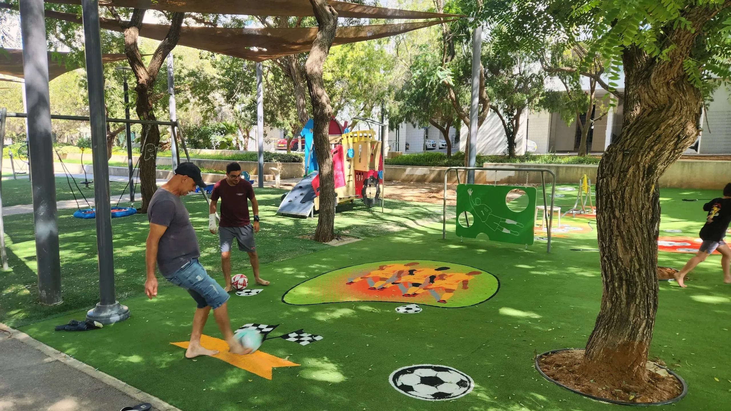 Children and adults playing football on a ColorPlay turf play lawn
