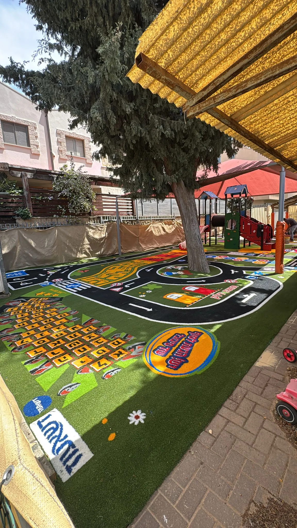 Colorful road-and-city play surface with winding roads and roundabouts in a kindergarten yard