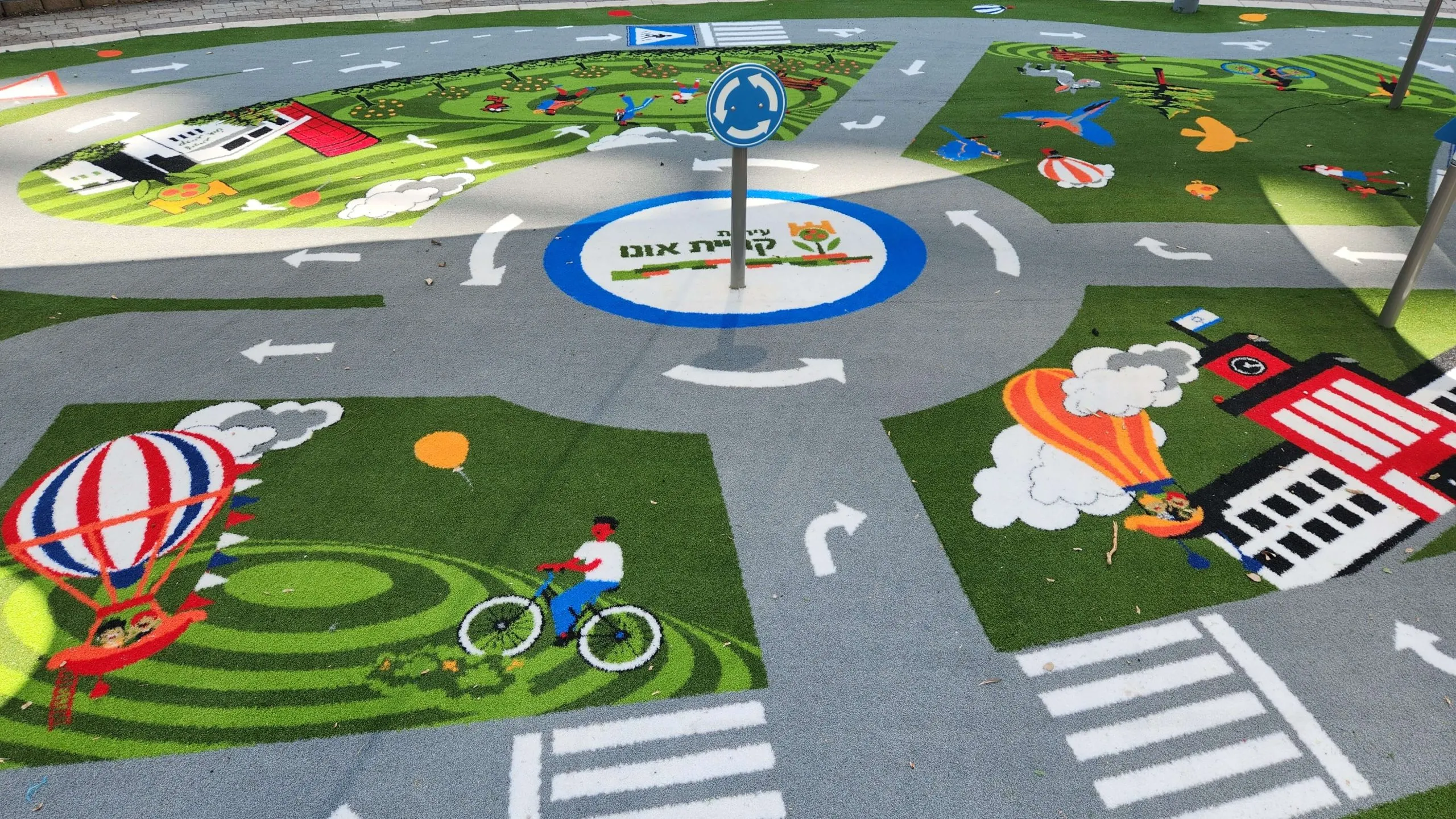 Road-circuit play surface with a roundabout, hot-air balloons and a barn